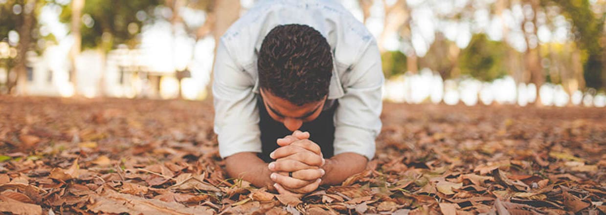 Uomo in ginocchio prostrato in preghiera